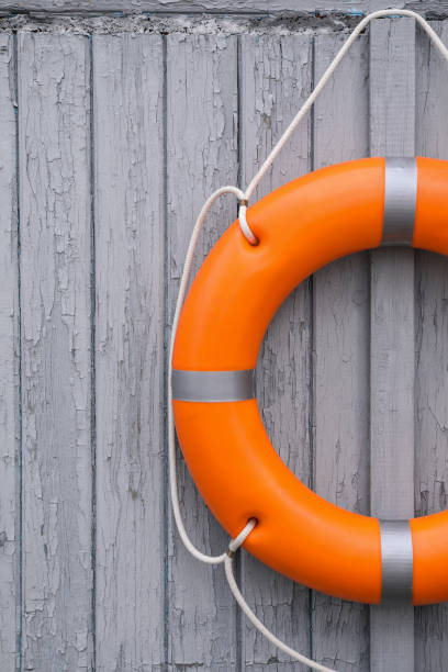 istock Orange life buoy hanging on light wooden wall 1406183606
