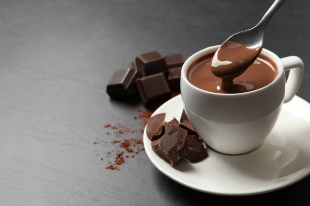 istock Spoon with yummy hot chocolate above cup on dark table, space for text 1406184083