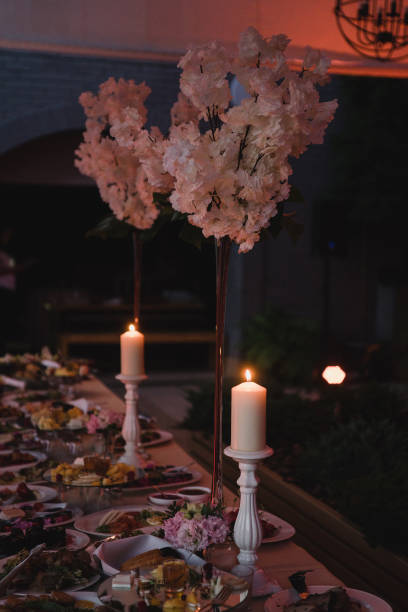 istock Table setting at the wedding reception. Floral compositions with beautiful flowers and greenery, candles, laying and plates on a decorated table. 1406184088