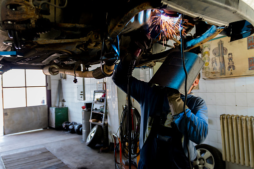 Skilled welder with mask doing the welding in a workshop.During the welding, there were a lot of sparks from the iron bar. Indicates a potentially hazardous situation.