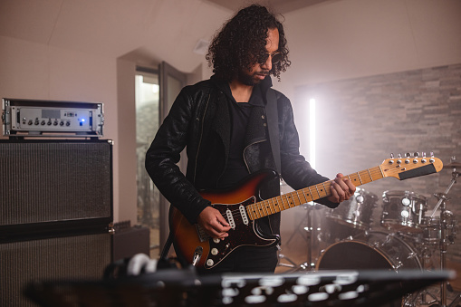 Male Hispanic Rock Guitarist Recording Guitar In A Recording Studio