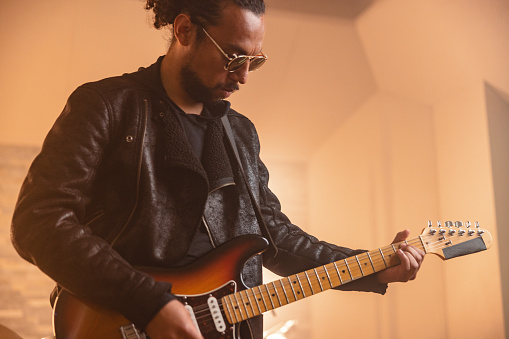 Male Hispanic Rock Guitarist Recording Guitar In A Recording Studio