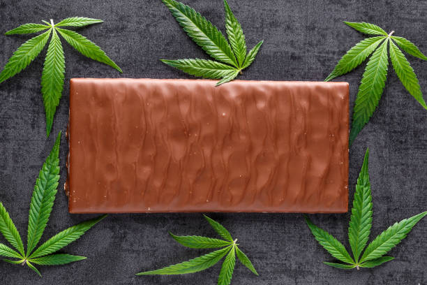 Marijuana leaves on top of chocolate.traditional sponge cake with cannabis weed cbd. Medical marijuana drugs in food dessert, ganja legalization.Stack of chocolate slices with mint leaf on a wooden table. stock photo