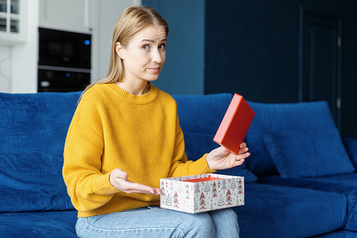 Thats not what i want. Portrait of dissatisfied sad woman with opened gift box looking at camera. Upset female disappointed with the bad birthday or terrible, horrible, awful anniversary present