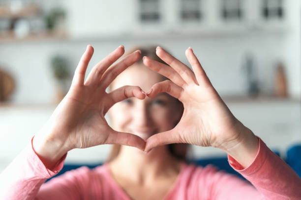 istock Happy young woman making heart shape gesture 1406187398