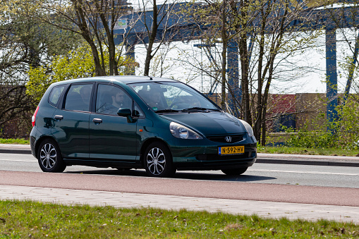 Hengelo, Twente, Overijssel, Netherlands, april 11th 2022, close-up of a Dutch  green 2003 Honda, 1st generation Jazz (aka Honda Fit) approaching on the 'Boekeloseweg' in Hengelo on a sunny day - the Jazz is made by Japanese car manufacturer Honda since 2001

The Hengelo municipality has a population of 82.000 (2022)