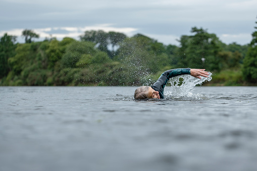 A medium wide angle view of a woman who is open water swimming in Northumberland in the North East of England. She is having a mindful evening in the water on her own.