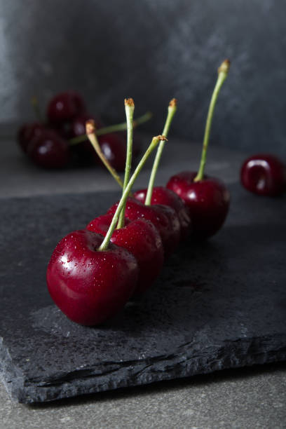 istock Red juicy cherry on a dark stone stand close-up 1406192668