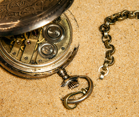 Antique pocket watch from 1917 with an old U.S silver dollar on black background.