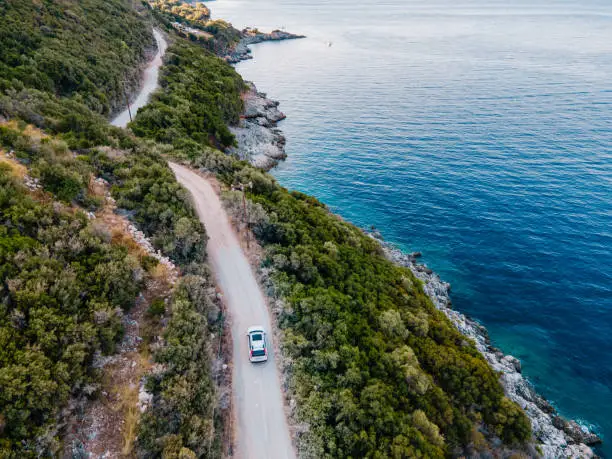 overhead view of car moving by road next to sea shore copy space