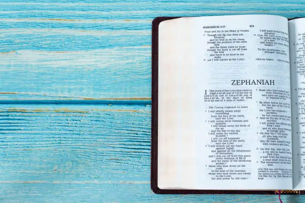 Zephaniah open Holy Bible Book on a rustic wooden background with copy space. Top table view. Old Testament Scripture prophecy study, Christian biblical concept.