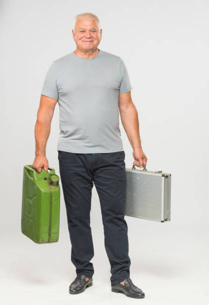 adult man with a metal suitcase for money in his water hand and a gas canister in his second hand in full growth on a white background isolated stock photo
