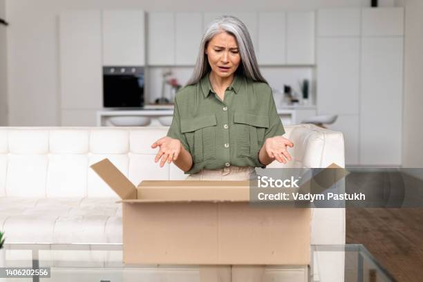 Disappointed Middleaged Asian Lady Upset With An Online Purchase Stock Photo - Download Image Now