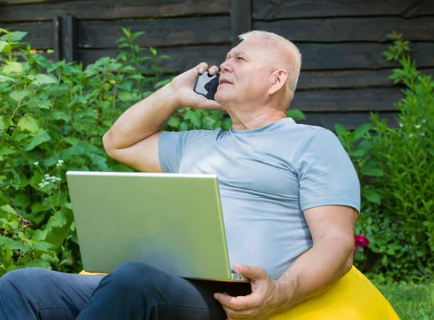 istock senior man using smartphone and laptop in the garden 1406205498