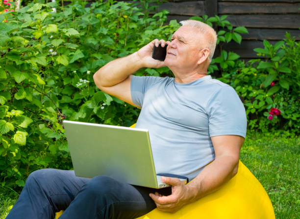 istock senior man using smartphone and laptop in the garden 1406205528
