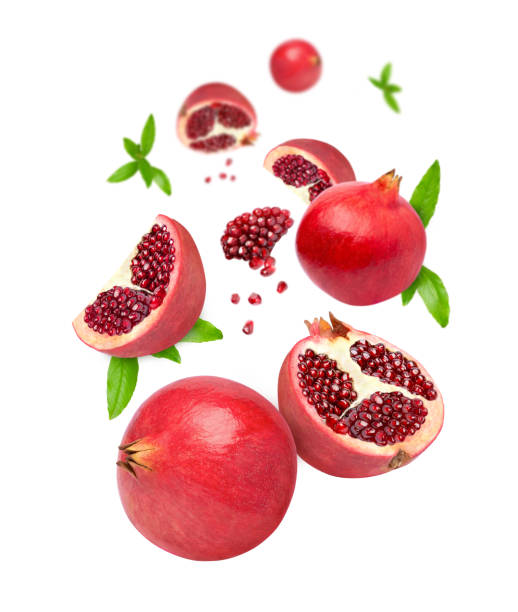 Pomegranate with seeds and half slice flying in the air isolated on white