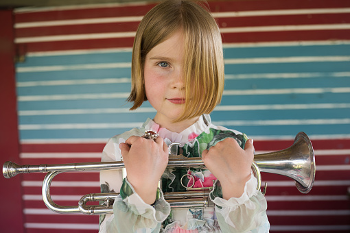 Portrait of a little girl. It's summer and she's about to perform a little garden concert with her trumpet.
