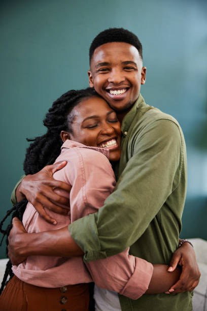 istock Affectionate young couple hugging while standing together in their living room 1406209277