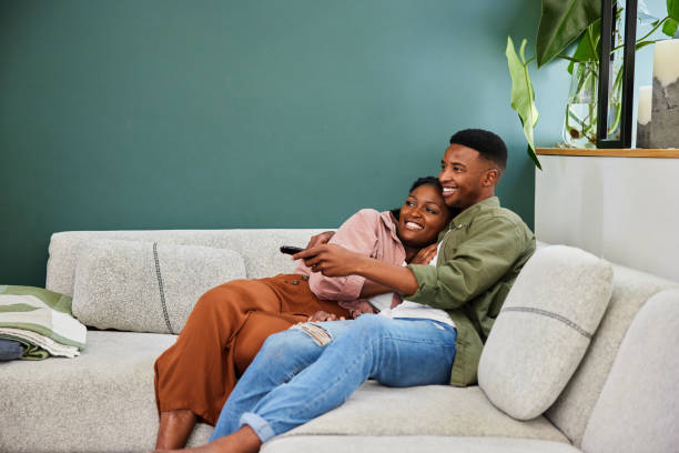 istock Smiling young couple watching television while relaxing on their sofa 1406209426