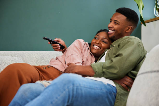istock Smiling young couple watching tv while sitting together on their sofa 1406209439