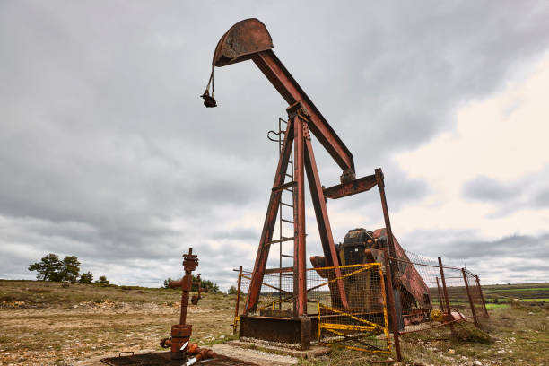 istock Oil pumping machine. Pump jack and windmills. Global warming 1406212690