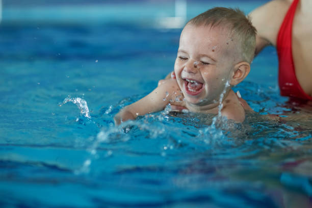 little kid boy learns to swim and has fun in pool with mom support. - blue water swimming pool sports and fitness imagens e fotografias de stock