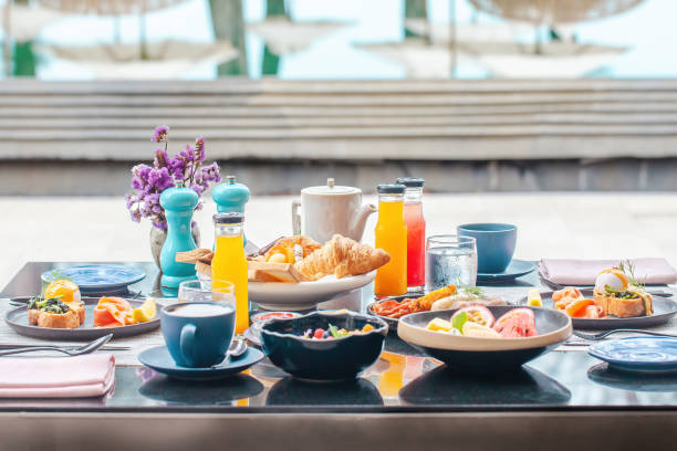 istock Served breakfast in luxury hotel. Poolside table with various healthy food, freshly squeezed juices, eggs, fruits and smoothie bawl. Morning buffet food in front of swimming pool in modern resort 1406215862