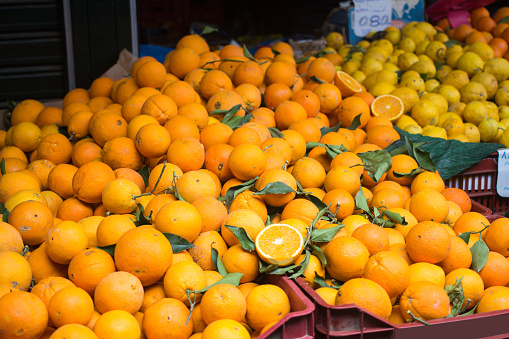Fresh organic juicy orange fruits, lemons, mandarins lying on counter on street food market, farmers fair, greengrocer's shop. Colorful food, healthy vegan vegetarian lifestyle concept.