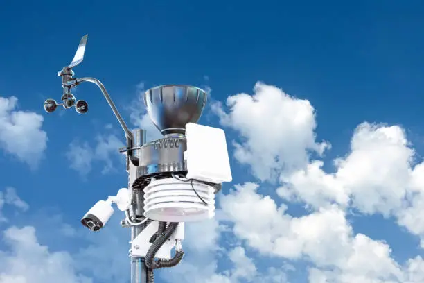 Automatic weather station, with a weather monitoring system and video cameras for observation. Against the background bright sun and summer cumulonimbus clouds
