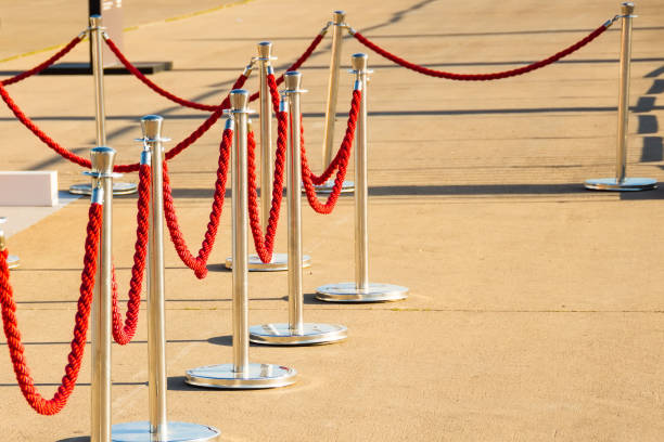 istock Silver plated barrier posts with red velvet ropes with red event carpet. 1406218279