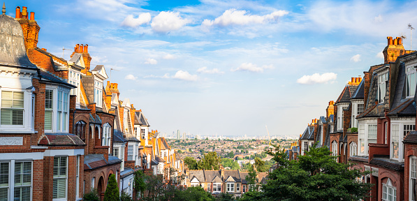A panoramic image looking down from streets of traditional Victorian houses in London's Muswell Hill suburb, towards the city centre on the horizon.
