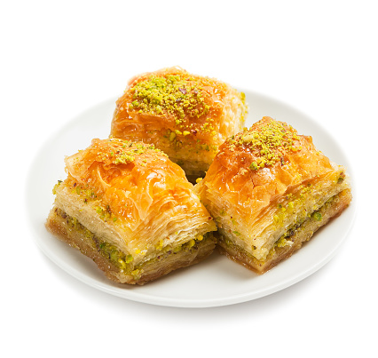 baklava with pistachios, 3 pieces, on a white plate, isolated, side view, close-up
