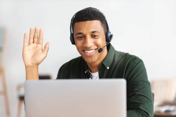 istock African american young man customer support call center operator or receptionist sitting at the workplace in a modern office consulting a client, uses a headset, smiles friendly 1406229511