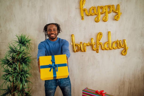 Happy young African man holding birthday gift box