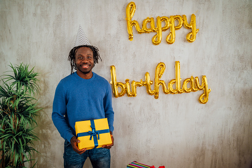 Happy young African man holding birthday gift box
