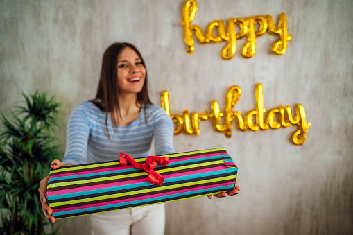 Happy young beautiful woman holding birthday gift box