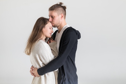 Portrait of a young caucasian couple hugging lovers on a white background.