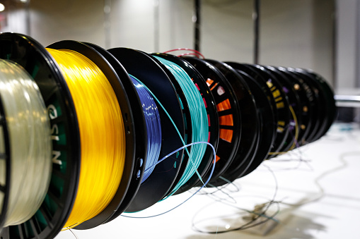 Side view of Colorful plastic PLA and ABS spools with filament for printing on a 3D printer.