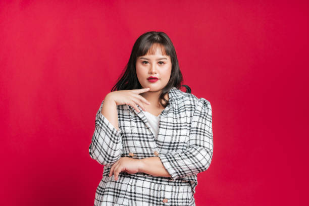 Portrait beautiful confidence Asian woman plus size model posing on isolate studio red background. stock photo