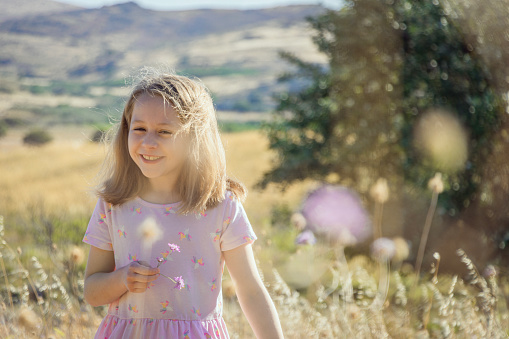 An 8 year old girl with blond hair is laughing in a country field. Photo taken on Lemnos island in Greece.