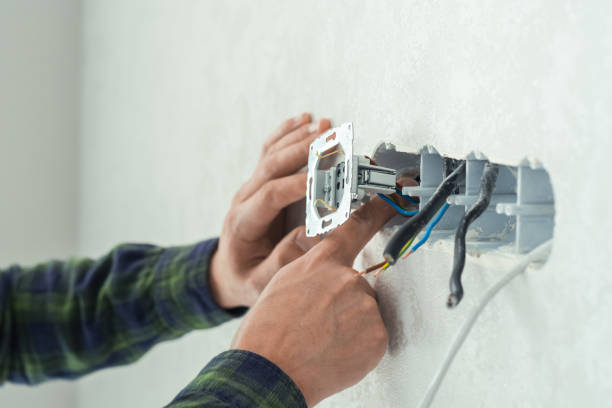 istock Electrician mounts a new socket on a white wall. Renovation process in a new apartment 1406235977