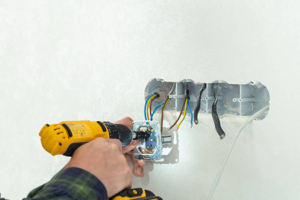 istock Electrician mounts a new socket on a white wall. Renovation process in a new apartment 1406236060