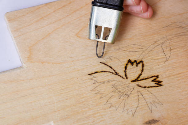 Burn out a drawing on a wooden board with an electric device with a scorcher