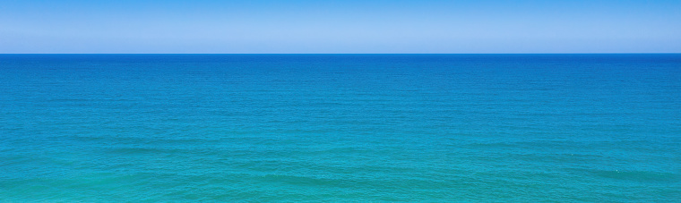 Seascape minimal panoramic background. Clear sky, horizon over blue waves