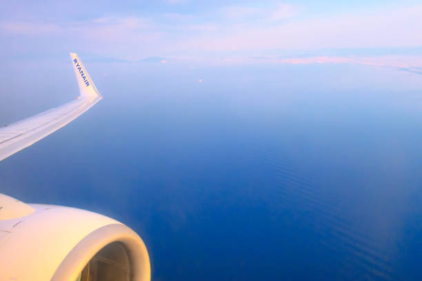 Athens, Greece - April 22, 2019: Low-cost airline Ryanair logo on airplane's wing and turbine, blue sea and Athens coastline