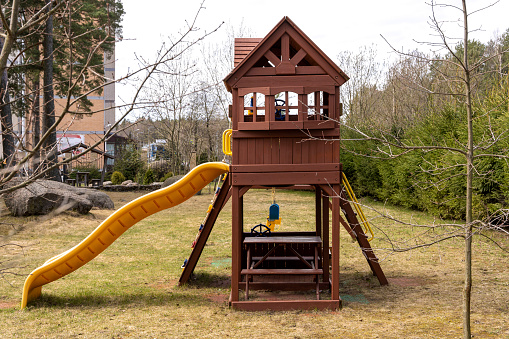 children's wooden playhouse with slide in the yard of the house on the playground