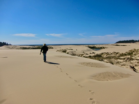 A hiker treks over the Umpqua Dunes and around the ponds off the Oregon Coast. Oregon Dunes National Recreation Area is on the Oregon Coast, stretching approximately 40 miles north of the Coos River in North Bend to the Siuslaw River in Florence, and adjoining Honeyman State Park on the west.