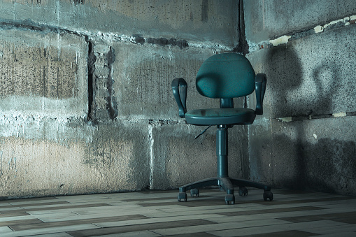 a chair in the basement. The interrogation chair. An old chair in a concrete basement. An empty chair in a concrete bunker