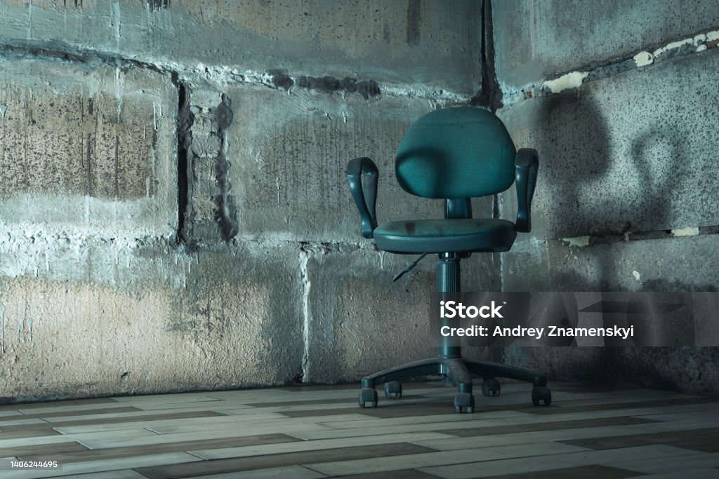 The interrogation chair. An old chair in a concrete basement. a chair in the basement. The interrogation chair. An old chair in a concrete basement. An empty chair in a concrete bunker Chair Stock Photo