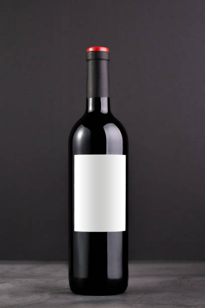 istock Single red wine bottle with blank label for mockup on dark gray background 1406248136